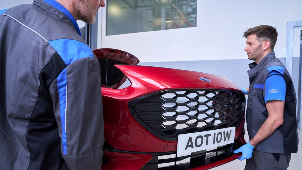 Ford technicians fitting a body panel to a repaired car